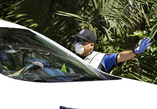 Police check cars and pedestrians at a checkpoint at the entrance to the Village of Key Biscayne, Fla., Monday, March 23, 2020. The village issued an emergency order, banning all travel, starting Monday, within the village by non-residents, with a few exceptions. (AP Photo/Wilfredo Lee)