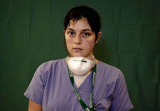 Lucia Perolari, 24, a nurse at the Humanitas Gavazzeni Hospital in Bergamo, Italy poses for a portrait at the end of her shift Friday, March 27, 2020. The intensive care doctors and nurses on the front lines of the coronavirus pandemic in Italy are almost unrecognizable behind their masks, scrubs, gloves and hairnets. (AP Photo/Antonio Calanni)