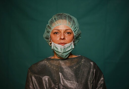 Laura Orsini, 39, an administrative worker at Rome's COVID 3 Spoke Casalpalocco Clinic poses for a portrait, Friday, March 27, 2020, during a break in her daily shift. The intensive care doctors and nurses on the front lines of the coronavirus pandemic in Italy are almost unrecognizable behind their masks, scrubs, gloves and hairnets. (AP Photo/Domenico Stinellis