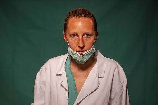 Doctor Marta Catoni, 33, an immunologist at Rome's COVID 3 Spoke Casalpalocco Clinic, poses for a portrait, Friday, March 27, 2020, during a break in her daily shift. The doctors and nurses on the front lines of the coronavirus pandemic in Italy are almost unrecognizable behind their masks, scrubs, gloves and hairnets - the flimsy battle armor donned at the start of each shift as the only barrier to contagion. (AP Photo/Domenico Stinellis)