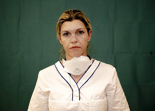 Daniela Turno, 34, an ICU nurse at the Humanitas Gavazzeni Hospital in Bergamo, Italy poses for a portrait at the end of her shift Friday, March 27, 2020. The intensive care doctors and nurses on the front lines of the coronavirus pandemic in Italy are almost unrecognizable behind their masks, scrubs, gloves and hairnets. &quot;What we are living through is like a tattoo,&quot; said Daniela Turno, an ICU nurse at the Humanitas Gavazzeni hospital in Bergamo. &quot;It will remain forever.&quot; (AP Photo/Antonio Calanni)