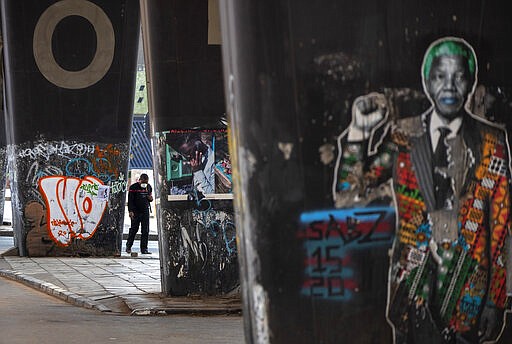 A man wearing a face masks walks on the street at Maboneng in Johannesburg, South Africa, Saturday, March 28, 2020. South Africa went into a nationwide lockdown for 21 days in an effort to control the spread of the COVID-19 coronavirus. The new coronavirus causes mild or moderate symptoms for most people, but for some, especially older adults and people with existing health problems, it can cause more severe illness or death. (AP Photo/Themba Hadebe)