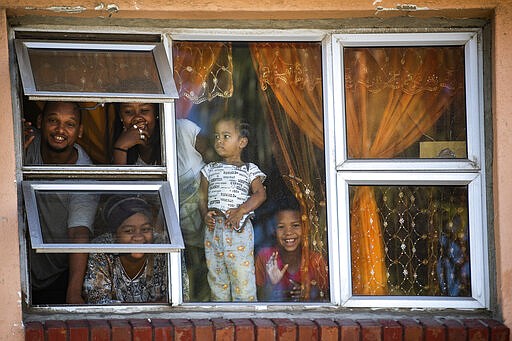 Residents look from their apartment windows reacting to the photographer outside, in Mannenburg, Cape Town, South Africa Saturday, March 28, 2020. South Africa went into a nationwide lockdown to restrict public movements for 21 days in an effort to control the spread of the COVID-19 coronavirus. (AP Photo)