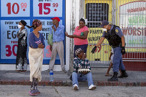 A policeman orders a loitering man to get home while patrolling in Mannenburg, Cape Town, South Africa, Saturday, March 28, 2020.  South Africa went into a nationwide lockdown to restrict public movements for 21 days in an effort to control the spread of the COVID-19 coronavirus.  (AP Photo)