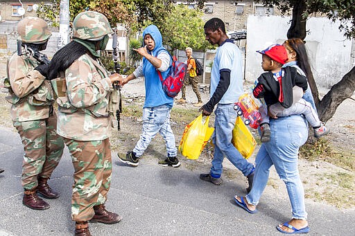 Soldiers interact with resident while on patrol in Mannenburg, Cape Town, South Africa Saturday, March 28, 2020. South Africa went into a nationwide lockdown to restrict public movements for 21 days in an effort to control the spread of the virulent COVID-19 coronavirus.(AP Photo)