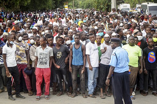 Kenyan police hold back ferry passengers after new measures aimed at halting the spread of the new coronavirus instead caused a crowd to form outside the ferry in Mombasa, Kenya Friday, March 27, 2020. The new measures required public transport vehicles to drop passengers 1km away and walk to the ferry terminal and then queue, but passengers fearing they would get stuck before a 7pm curfew started crowding to get on causing police to fire tear gas and round up the passengers. (AP Photo)