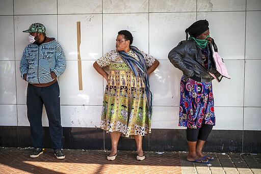 Residents of the Yeoville neighborhood of Johannesburg queue to enter a grocery store Saturday, March 28, 2020. South Africa went into a nationwide lockdown for 21 days in an effort to control the spread of the highly contagious COVID-19 coronavirus. (AP Photo/Jerome Delay)