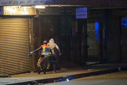 A police officer chases a man who violated the lockdown downtown Johannesburg, South Africa, Friday, March 27, 2020. Police and army started patrolling moments after South Africa went into a nationwide lockdown for 21 days in an effort to mitigate the spread to the coronavirus. The new coronavirus causes mild or moderate symptoms for most people, but for some, especially older adults and people with existing health problems, it can cause more severe illness or death.(AP Photo/Jerome Delay)