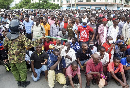 Kenyan police hold back ferry passengers after new measures aimed at halting the spread of the new coronavirus instead caused a crowd to form outside the ferry in Mombasa, Kenya Friday, March 27, 2020. The new measures required public transport vehicles to drop passengers 1km away and walk to the ferry terminal and then queue, but passengers fearing they would get stuck before a 7pm curfew started crowding to get on causing police to fire tear gas and round up the passengers. (AP Photo)