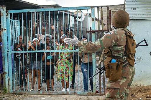 South African National Defense Forces patrol the densely populated Alexandra township east of Johannesburg Friday, March 27, 2020. South Africa went into a nationwide lockdown for 21 days in an effort to mitigate the spread to the coronavirus, but in Alexandra, many people were gathering in the streets disregarding the lockdown. The new coronavirus causes mild or moderate symptoms for most people, but for some, especially older adults and people with existing health problems, it can cause more severe illness or death.(AP Photo/Jerome Delay)