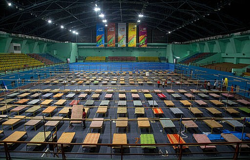 Indian workers arrange beds to prepare a quarantine center at the Sarusojai sports complex in Gauhati, India, Saturday, March 28, 2020. The new coronavirus causes mild or moderate symptoms for most people, but for some, especially older adults and people with existing health problems, it can cause more severe illness or death. (AP Photo/Anupam Nath)