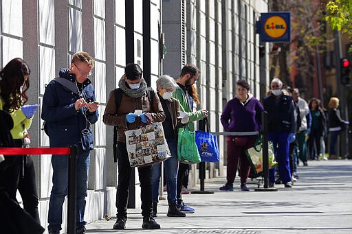 People line up to buy supplies from a supermarket during the coronavirus outbreak in Madrid, Spain, Saturday, March 28, 2020. The highly contagious CODIC-19 coronavirus has impacted on society around the globe, with many people self imposing isolation, and social distancing when they move from their homes. (AP Photo/Manu Fernandez)