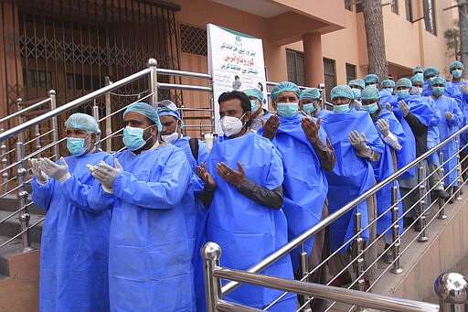 Hospital staff pray before joining their shift, outside a hospital setup for coronavirus infected patients in Quetta, Pakistan, Thursday, March 26, 2020. The virus causes mild or moderate symptoms for most people, but for some, especially older adults and people with existing health problems, it can cause more severe illness or death. (AP Photo/Arshad Butt)