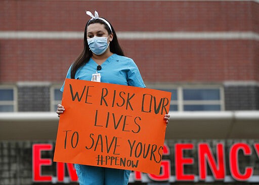 A nurse demonstrates outside the emergency entrance at Jacobi Medical Center in the Bronx borough of New York, Saturday, March 28, 2020, demanding more personal protective equipment for medical staff treating coronavirus patients. A member of the New York nursing community died earlier this week while treating coronavirus patients at another New York hospital. The city leads the nation in the number of COVID-19 cases, and the United States currently has the most cases in the world, according to the World Health Organization. (AP Photo/Kathy Willens)