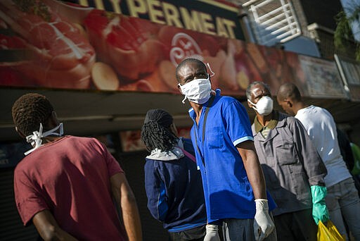 Residents of the Yeoville neighborhood of Johannesburg queue to enter a grocery store Saturday, March 28, 2020. South Africa went into a nationwide lockdown for 21 days in an effort to control the spread of the coronavirus. The COVID-19 coronavirus symptoms can include fever and cough but some suffer more severe symptoms like pneumonia and sometimes requiring hospitalization. (AP Photo/Jerome Delay)