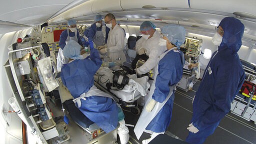 This GoPro image provided Saturday March 28, 2020 by the French Army shows doctors taking care of evacuated patients infected with the Covid-19 disease, aboard a military plane from Mulhouse, eastern France to Bordeaux, southwestern France, Friday March 27, 2020. France is evacuating its citizens infected with the coronavirus in Eastern France. The new coronavirus causes mild or moderate symptoms for most people, but for some, especially older adults and people with existing health problems, it can cause more severe illness or death. (Dicod via AP)