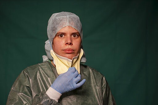 Claudia Accardo, ICU transport service at Rome's COVID 3 Spoke Casalpalocco Clinic, poses for a portrait, Friday, March 27, 2020, during a break in her daily shift. The intensive care doctors and nurses on the front lines of the coronavirus pandemic in Italy are almost unrecognizable behind their masks, scrubs, gloves and hairnets. But that flimsy battle armor donned at the start of each shift is their only barrier to contagion. (AP Photo/Domenico Stinellis)