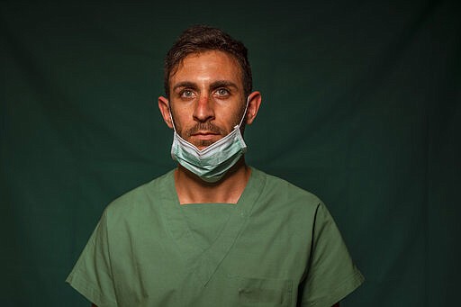 Daniele Rondinella, 30, an ICU nurse at Rome's COVID 3 Spoke Casalpalocco Clinic poses for a portrait, Friday, March 27, 2020, during a break in his daily shift. The intensive care doctors and nurses on the front lines of the coronavirus pandemic in Italy are almost unrecognizable behind their masks, scrubs, gloves and hairnets. (AP Photo/Domenico Stinellis)