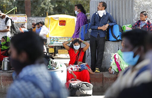 A migrant daily-wage laborer family wait for transportation to travel to their respective villages following a lockdown amid concern over spread of coronavirus in New Delhi, India, Friday, March 27, 2020. Some of India's legions of poor and others suddenly thrown out of work by a nationwide stay-at-home order began receiving aid on Thursday, as both public and private groups worked to blunt the impact of efforts to curb the coronavirus pandemic. The measures that went into effect Wednesday, the largest of their kind in the world, risk heaping further hardship on the quarter of the population who live below the poverty line and the 1.8 million who are homeless. (AP Photo/Manish Swarup)