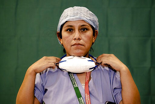 Ana Travezano, 39, a nurse at the Humanitas Gavazzeni Hospital in Bergamo, Italy poses for a portrait at the end of her shift Friday, March 27, 2020. The intensive care doctors and nurses on the front lines of the coronavirus pandemic in Italy are almost unrecognizable behind their masks, scrubs, gloves and hairnets. But that flimsy battle armor donned at the start of each shift is their only barrier to contagion. (AP Photo/Antonio Calanni)