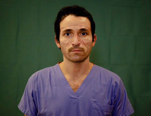 Doctor Luca Tarantino, 37, an electrophysiologist at the Humanitas Gavazzeni Hospital in Bergamo, Italy poses for a portrait at the end of his shift Friday, March 27, 2020. The intensive care doctors and nurses on the front lines of the coronavirus pandemic in Italy are almost unrecognizable behind their masks, scrubs, gloves and hairnets. (AP Photo/Antonio Calanni)