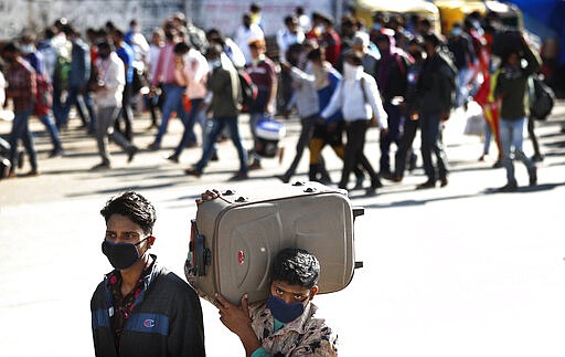 Migrant daily wage laborers make the journey to their respective villages on foot following a lockdown amid concern over spread of coronavirus in New Delhi, India, Friday, March 27, 2020. Some of India's legions of poor and others suddenly thrown out of work by a nationwide stay-at-home order began receiving aid on Thursday, as both public and private groups worked to blunt the impact of efforts to curb the coronavirus pandemic. The measures that went into effect Wednesday, the largest of their kind in the world, risk heaping further hardship on the quarter of the population who live below the poverty line and the 1.8 million who are homeless. (AP Photo/Manish Swarup)