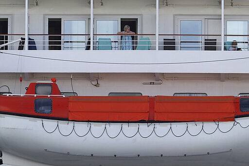 In this Friday, March 27, 2020, photo, passengers are seen on the cruise ship Artania docked at Fremantle harbour in Fremantle, Australia. Authorities were still hoping to fly 800 cruise ship passengers from Australia to Germany on the weekend, but a sharp overnight rise in cases of the new coronavirus on board brought severe complications for the repatriation mission. (Richard Wainwright/AAP Image via AP)