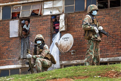 South African National Defense Forces patrol the Men's Hostel in the densely populated Alexandra township east of Johannesburg, Saturday, March 28, 2020, enforcing a strict lockdown in an effort to control the spread of the coronavirus. The new coronavirus causes mild or moderate symptoms for most people, but for some, especially older adults and people with existing health problems, it can cause more severe illness or death.(AP Photo/Jerome Delay)