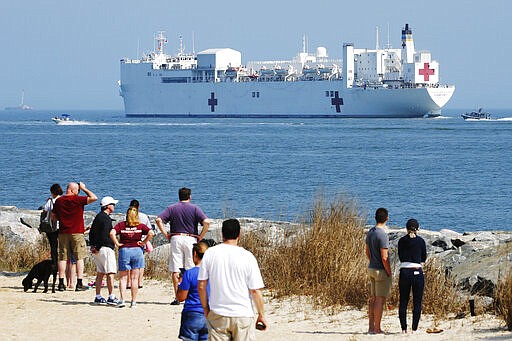 Local residents watch as the USNS Comfort departs Hampton Roads en route to New York to help in the response to the coronavirus outbreak Saturday, March 28, 2020, in Hampton, Va. (AP Photo/Steve Helber)