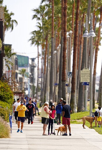 Pedestrians walk along a closed Venice Beach boardwalk, Saturday, March 28, 2020, in Los Angeles. With cases of coronavirus surging and the death toll surpassing 100, lawmakers are pleading with cooped-up Californians to spend a second weekend at home to slow the spread of the infections. It has been more than a week since Gov. Gavin Newsom barred 40 million residents from going outdoors except for essentials. Even so, reports of crowds have prompted local and state officials to warn that ignoring social distancing, park and beach closures could spread the virus, which already is surging. The new coronavirus causes mild or moderate symptoms for most people, but for some, especially older adults and people with existing health problems, it can cause more severe illness or death. (AP Photo/Mark J. Terrill)