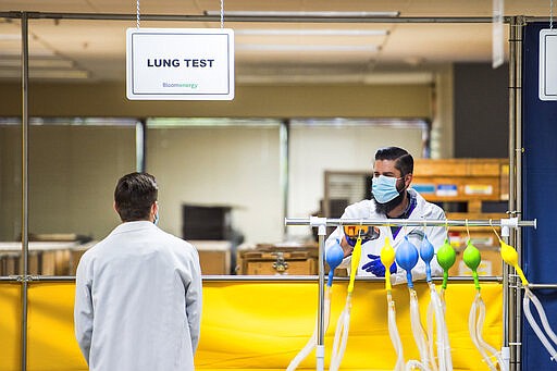 Staff of Bloom Energy work at a lung testing station for ventilators in Sunnyvale, Calif., Saturday, March 28, 2020. Bloom Energy is a fuel cell generator company that has switched over to refurbishing ventilators as an increasing number of patients experience respiratory issues as a result of COVID-19. (Beth LaBerge/Pool Photo via AP)