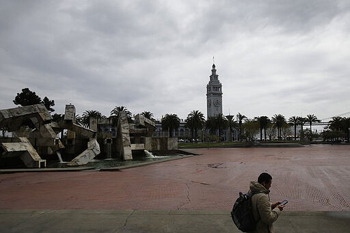 A man walks in an empty Justin Herman Plaza in San Francisco, Saturday, March 28, 2020. (AP Photo/Jeff Chiu)