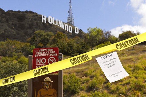 A sign is seen at the entrance to Innsdale Trail near the Hollywood Sign, Saturday, March 28, 2020, in Los Angeles. With cases of coronavirus surging and the death toll surpassing 100, lawmakers are pleading with cooped-up Californians to spend a second weekend at home to slow the spread of the infections. It has been more than a week since Gov. Gavin Newsom barred 40 million residents from going outdoors except for essentials. Even so, reports of crowds have prompted local and state officials to warn that ignoring social distancing, park and beach closures could spread the virus, which already is surging.  (AP Photo/Mark J. Terrill)