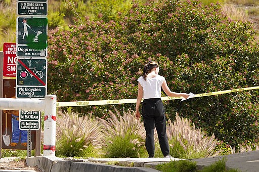 A hiker looks at sign indicating that the entrance to Innsdale Trail was closed before ignoring it and going in near the Hollywood Sign, Saturday, March 28, 2020, in Los Angeles. With cases of coronavirus surging and the death toll surpassing 100, lawmakers are pleading with cooped-up Californians to spend a second weekend at home to slow the spread of the infections. It has been more than a week since Gov. Gavin Newsom barred 40 million residents from going outdoors except for essentials. Even so, reports of crowds have prompted local and state officials to warn that ignoring social distancing, park and beach closures could spread the virus, which already is surging. (AP Photo/Mark J. Terrill)