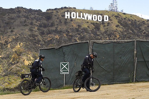 Los Angeles police officers patrol near the Hollywood Sign, Saturday, March 28, 2020, in Los Angeles. With cases of coronavirus surging and the death toll surpassing 100, lawmakers are pleading with cooped-up Californians to spend a second weekend at home to slow the spread of the infections. It has been more than a week since Gov. Gavin Newsom barred 40 million residents from going outdoors except for essentials. Even so, reports of crowds have prompted local and state officials to warn that ignoring social distancing, park and beach closures could spread the virus, which already is surging.  (AP Photo/Mark J. Terrill)