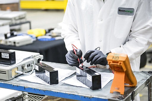 David Yee, an NPI mechanical engineer, tests voltage of new batteries at Bloom Energy in Sunnyvale, Calif., Saturday, March 28, 2020. Bloom Energy is a fuel cell generator company that has switched over to refurbishing ventilators as an increasing number of patients experience respiratory issues as a result of COVID-19. (Beth LaBerge/Pool Photo via AP)