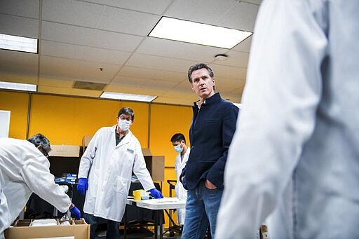 California Gov. Gavin Newsom, center right, is given a tour of the Bloom Energy Sunnyvale, Calif., campus Saturday, March 28, 2020. Bloom Energy is a fuel cell generator company that has switched over to refurbishing ventilators as an increasing number of patients experience respiratory issues as a result of COVID-19. (Beth LaBerge/KQED via AP, Pool)