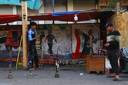 Int his Thursday, March 19, 2020 photo, a man smokes waterpipe at Tahrir square, Baghdad, Iraq. As the coronavirus spreads across the Middle East, cherished traditions are coming to an abrupt halt: no more coffee shops where men gather to play cards and backgammon. And most importantly, no more smoking of the beloved shisha, or waterpipe, in public places. (AP Photo/Khalid Mohammed)