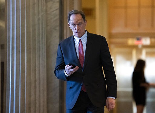 FILE - In this Feb. 3, 2020, file photo, Sen. Pat Toomey, R-Pa., walks at the Capitol in Washington. The nation's fiercest fiscal conservatives are largely embracing the massive economic rescue package moving through Congress. In many cases, those conservatives who support the $2 trillion coronavirus spending bill are the very same who raged against the $800 billion economic stimulus package backed by the Obama administration after the 2008 financial crisis. (AP Photo/J. Scott Applewhite, File)