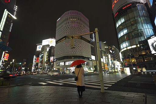 FILE - In this March 28, 2020, file, photo, a woman stands at empty Ginza shopping district in Tokyo Saturday, March 28, 2020. Before the Olympics were postponed, Japan looked like it had coronavirus infections contained, even as they spread in neighboring countries. Now that the games have been pushed to next year, Tokyo&#146;s cases are spiking, and the city's governor is requesting that people stay home, even hinting at a possible lockdown. (AP Photo/Eugene Hoshiko, File)