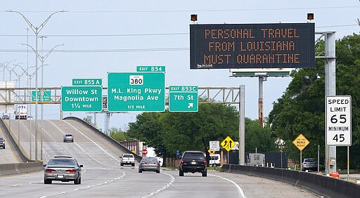 A sign along I-10 informing persons who travel from Louisiana to quarantine is shown Sunday, March 29, 2020, in Beaumont, Texas. The state is ratcheting up restrictions on neighboring Louisiana, one of the growing hot spots for coronavirus in the U.S. Just two days after Texas began requiring airline passengers from New Orleans to comply with a two-week quarantine, Texas Gov. Greg Abbott said state troopers will now also patrol highway entry points at the Louisiana border. (AP Photo/David J. Phillip)