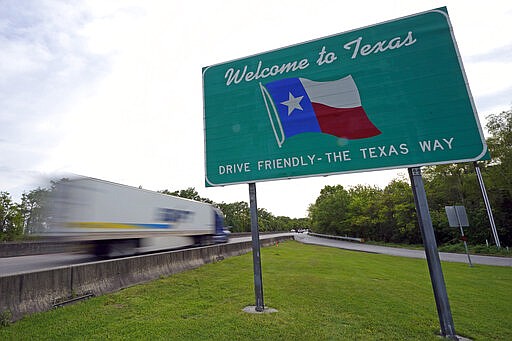 A truck passes a welcome sign along I-10 Sunday, March 29, 2020, in Orange, Texas, near the Louisiana border. Texas is ratcheting up restrictions on neighboring Louisiana, one of the growing hot spots for coronavirus in the U.S. Just two days after Texas began requiring airline passengers from New Orleans to comply with a two-week quarantine, Texas Gov. Greg Abbott said state troopers will now also patrol highway entry points at the Louisiana border. (AP Photo/David J. Phillip)