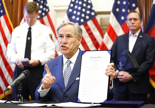 During a press conference at the Texas State Capitol in Austin, Texas Governor Greg Abbott holds a new executive order stating that travel from other states will be limited and subject to 14-day self quarantine, Sunday, March 29, 2020. He also announced the US Army Corps of Engineers and the state are putting up a 250-bed field hospital at the Kay Bailey Hutchison Convention Center in downtown Dallas The space can expand to nearly 1,400 beds. Joining him are Texas Division of Emergency Management Chief Nim Kidd (left) and former State Representative Dr. John Zerwas (right). (Tom Fox/The Dallas Morning News via AP, Pool)