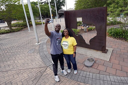 Gus and Mia Davis take a photograph at a rest stop Sunday, March 29, 2020, in Orange, Texas near the Louisiana border. The couple is moving from Washington D.C. to San Antonio. Texas is ratcheting up restrictions on neighboring Louisiana, one of the growing hot spots for coronavirus in the U.S. Just two days after Texas began requiring airline passengers from New Orleans to comply with a two-week quarantine, Texas Gov. Greg Abbott said state troopers will now also patrol highway entry points at the Louisiana border. (AP Photo/David J. Phillip)