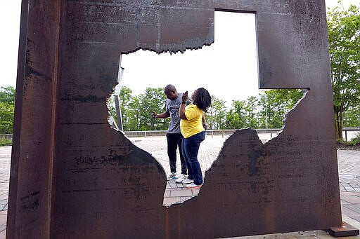 Gus and Mia Davis take a photograph at a rest stop, Sunday, March 29, 2020, in Orange, Texas, near the Louisiana border. The couple is moving from Washington, D.C. to San Antonio. Texas is ratcheting up restrictions on neighboring Louisiana, one of the growing hot spots for coronavirus in the U.S. Just two days after Texas began requiring airline passengers from New Orleans to comply with a two-week quarantine, Texas Gov. Greg Abbott said state troopers will now also patrol highway entry points at the Louisiana border. (AP Photo/David J. Phillip)