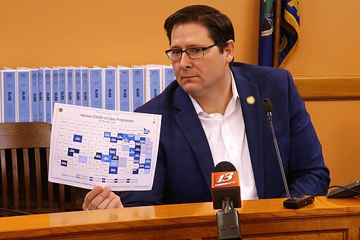 Kansas House Speaker Ron Ryckman Jr., R-Olathe, holds up a map showing the spread of the novel coronavirus in the state by county, during a meeting of legislative leaders, Sunday, March 29, 2020, at the Statehouse in Topeka, Kan. The counties in blue have had confirmed cases, with the most recent cases in the darkest shade. (AP Photo/John Hanna)