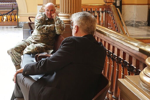 Maj. Gen. Lee Tafanelli, left, the state's emergency management director, confers with Tim Graham, right, a member of Gov. Laura Kelly's staff before a meeting of legislative leaders to review a statewide stay-at-home order, keeping a 6-foot space between them, Sunday, March 29, 2020, at the Statehouse in Topeka, Kan. Legislative leaders agreed that the order is necessary to check the spread of the novel coronavirus. (AP Photo/John Hanna)