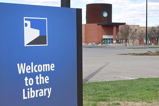 In this photo from Friday, March 28, 2020, the parking lot of the Topeka and Shawnee County Public Library sits empty with the library closed in Topeka, Kan. because of the coronavirus outbreak. Kansas Gov. Laura Kelly has issued a stay-at-home order for all 2.9 million of the state's residents. (AP Photo/John Hanna)