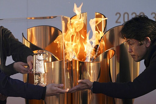 FILE - In this March 25, 2020, file, photo, officials light a lantern from the Olympic Flame at the end of a flame display ceremony in Iwaki, northern Japan. Before the Olympics were postponed, Japan looked like it had coronavirus infections contained, even as they spread in neighboring countries. Now that the games have been pushed to next year, Tokyo&#146;s cases are spiking, and the city's governor is requesting that people stay home, even hinting at a possible lockdown. (AP Photo/Eugene Hoshiko, File)