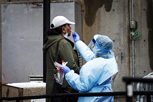 A patient is given a COVID-19 test by a medical worker outside Brooklyn Hospital Center, Sunday, March 29, 2020, in Brooklyn borough of New York. The new coronavirus causes mild or moderate symptoms for most people, but for some, especially older adults and people with existing health problems, it can cause more severe illness or death. (AP Photo/John Minchillo)